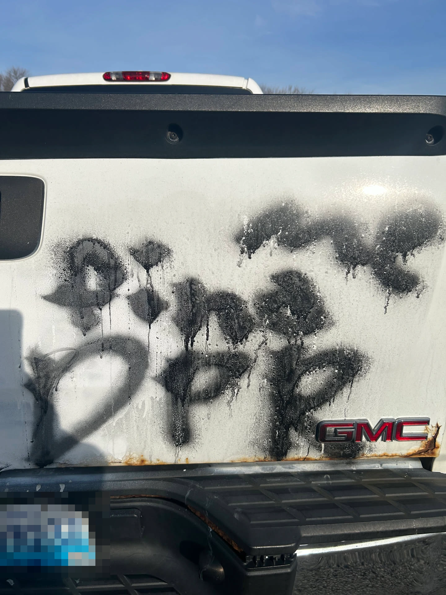 Image of the same white truck, but with black spray paint in a different locaiton on the back. The text is clearer, it says 'find me DPR'.